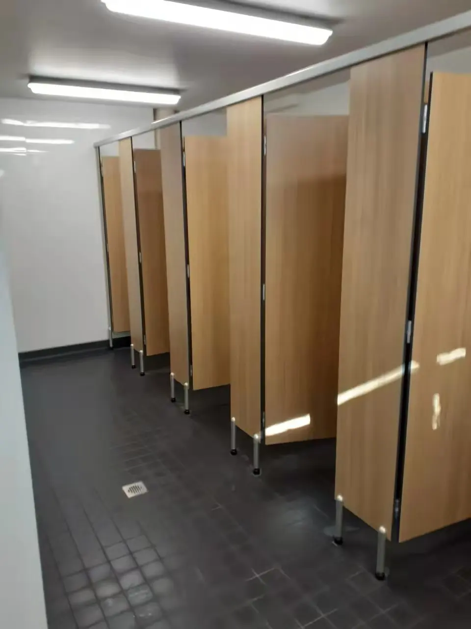 Clean shared commercial washroom with toilet cubicles and tiled floor