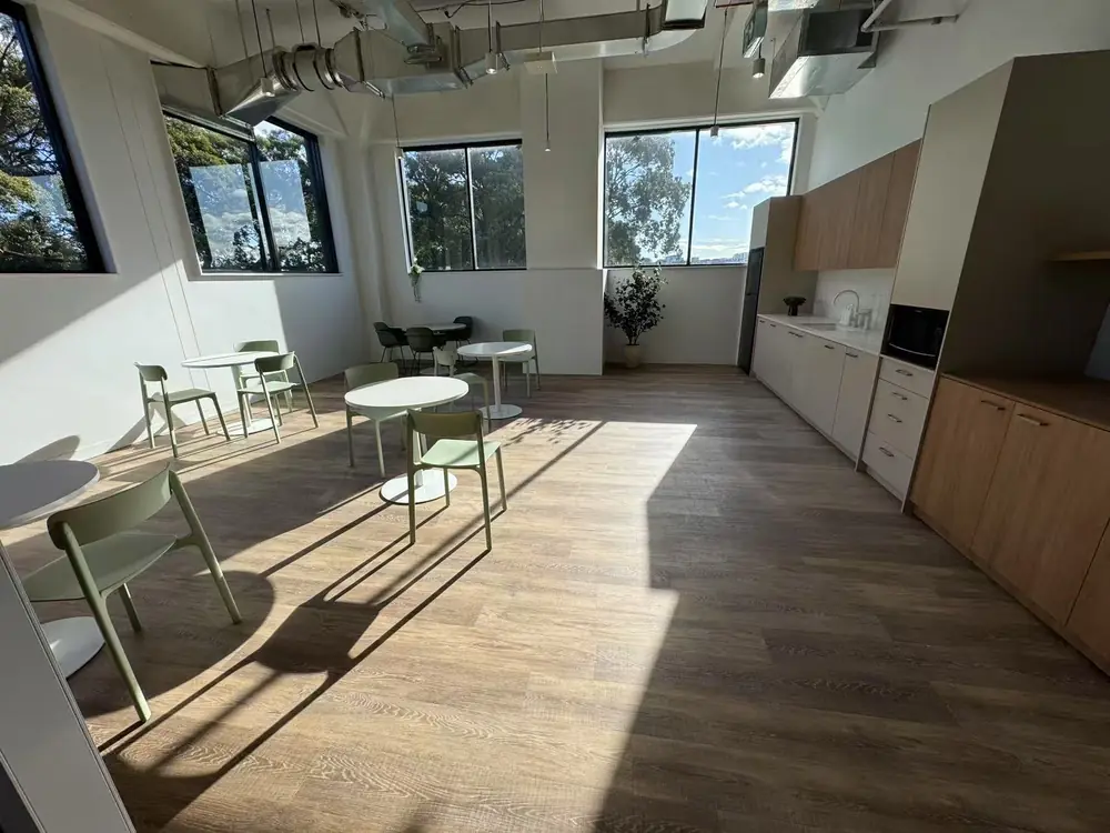 Clean office lunchroom with tables, chairs and kitchen